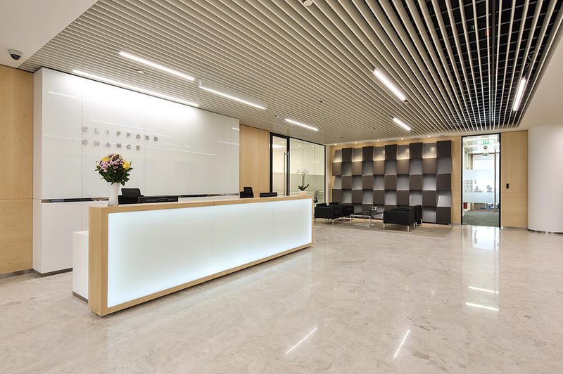 Long view of the reception at Clifford Chance&#x27;s offices, gleaming with white and and light pink decor